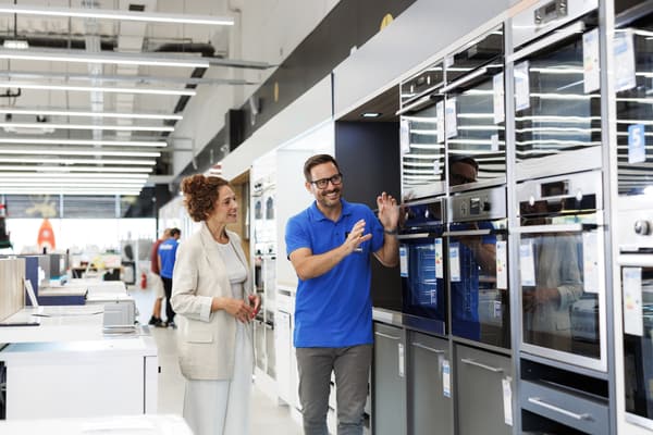 iStock Credit: Riska An appliance salesperson demonstrating ovens to a buyer